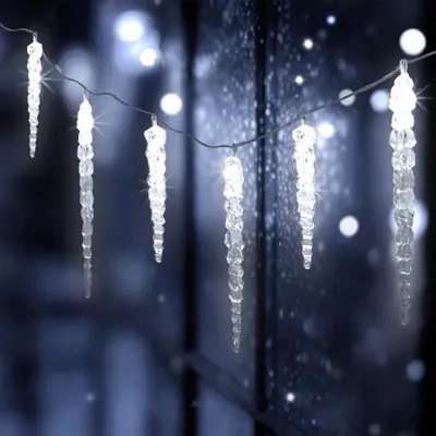 Icicle lights are strung across a window with a snowy or frosty effect.