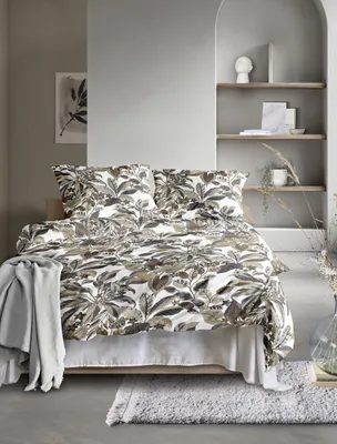 A bedroom scene with a bed dressed in patterned bedding, a blanket, and a rug.