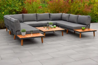 An outdoor sectional sofa set with coffee tables on a patio.