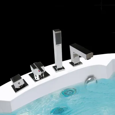 A close-up view of a modern bathtub faucet set with a handheld showerhead, mounted on the edge of a white bathtub filled with blue water.