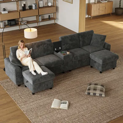 A woman is reading a book on a sectional sofa in a living room.