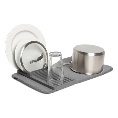 A dish drying mat with plates, a pot lid, a glass, and a pot.
