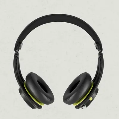 A pair of black headphones with green accents is shown from a top-down perspective against a light gray background.
