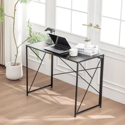 A small black folding desk with a laptop, books, and a plant in a pot, placed near a window.