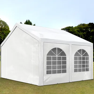 A white party tent is set up on a grassy lawn with trees and a blue sky in the background.