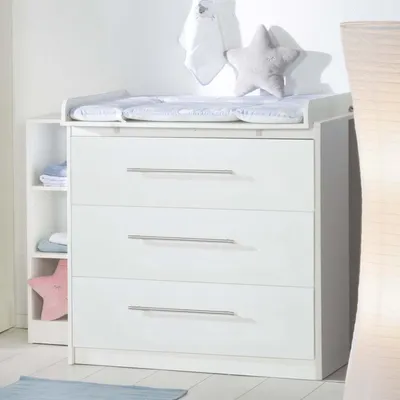 A white baby changing dresser with three drawers and an attached changing pad.