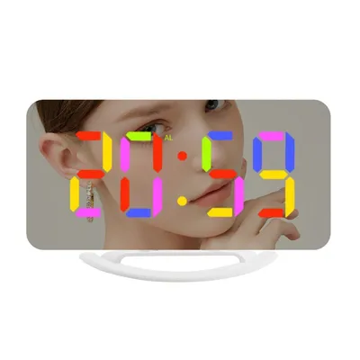 A digital alarm clock with a mirrored display showing the time and a person's face reflected.