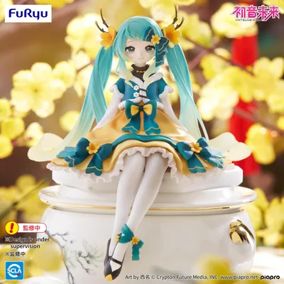 A Hatsune Miku figurine is displayed sitting on a decorative white base, with a blurred background of yellow flowers.