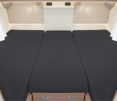 A view of a three-part bed setup in a camper or caravan, with dark grey fitted sheets on each section.