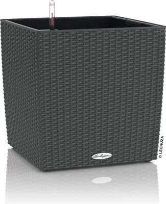 A square, dark gray planter with a woven texture sits on a reflective white surface.
