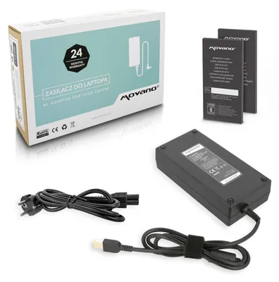 A product shot of a laptop AC adapter and its accessories, including the box, power brick, and cables, arranged on a white and light gray surface.