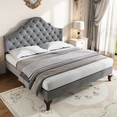 A gray upholstered bed with a tufted headboard is shown in a bedroom setting.