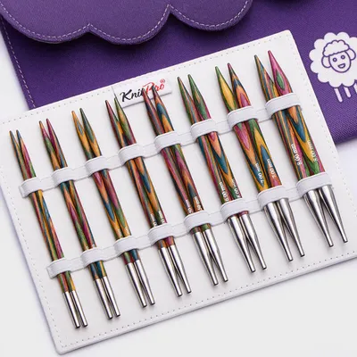 A set of knitting needles laid out in a white case, with a purple fabric case in the background.