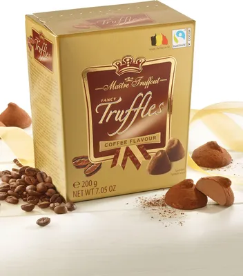 A box of Maitre Truffout Fancy Gold Truffles with coffee beans and truffles scattered around it.