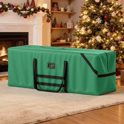 A green storage bag for a Christmas tree is placed on a rug in front of a fireplace and a decorated Christmas tree.