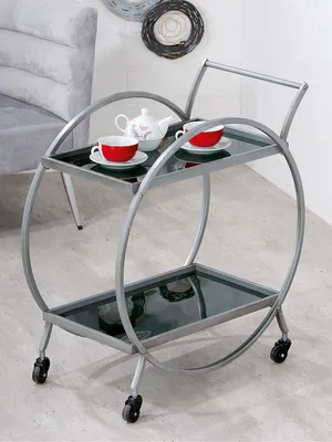 A serving trolley with tea set on it, in a room with a sofa and wall decorations.