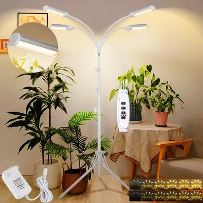 A plant grow light stand with multiple LED heads is shown in a room with several potted plants, a table with a tablecloth, and a chair.