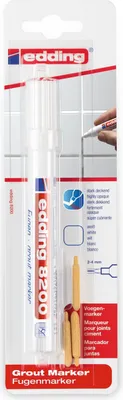 The image shows the packaging of a grout marker, with a hand using the marker on a tiled surface in the background.