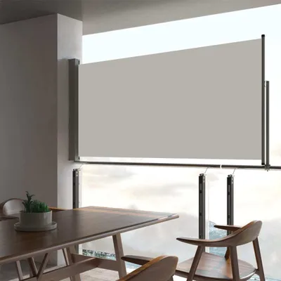 A dining area with a table and chairs, with a retractable side awning covering a large window overlooking a cloudy sky.