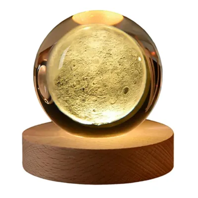 A crystal ball with a 3D moon design sits on a wooden base, illuminated from within.