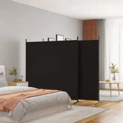 A bedroom scene with a black room divider set up behind a bed.