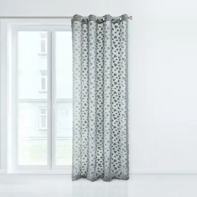 A single curtain hangs in front of a window.