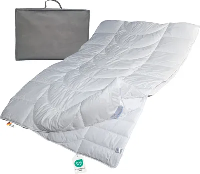 A white duvet is laid out diagonally on a white background, with a grey storage bag behind it.