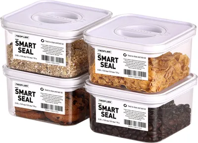 Four clear plastic food storage containers with white lids, stacked in pairs. Each container has a label with the brand name and product details.