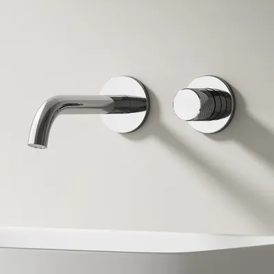 A modern chrome wall-mounted faucet and its control knob are mounted on a light-colored wall above a white sink.