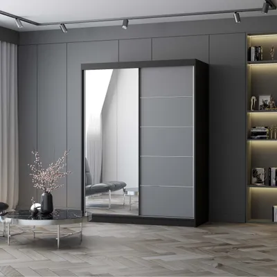 A modern bedroom with a large sliding door wardrobe with a mirrored front.