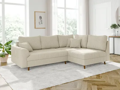 A beige corduroy sectional sofa is placed in a bright living room with large windows and wooden floors.