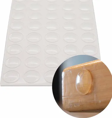 A sheet of clear, oval-shaped adhesive bumper pads is shown along with a close-up of one pad applied to a wooden surface.