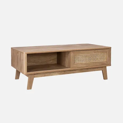 A wooden coffee table with a rattan drawer front and an open shelf, presented against a plain background.