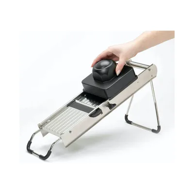 A hand is shown operating a mandoline slicer.