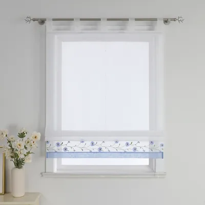 A white sheer Roman blind with a blue floral embroidered border and a solid blue band at the bottom, hanging on a window.
