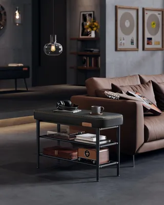 A modern living room with a brown leather sofa, a black shoe bench, and decorative items.