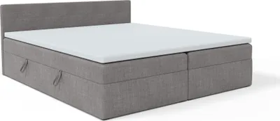 A grey boxspring bed with a white mattress topper, shown from a diagonal angle against a white background.