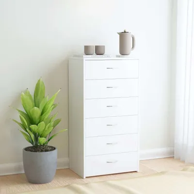 A white chest of drawers with a plant and decorative items on top, placed against a white wall.