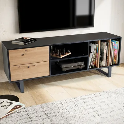 A modern TV stand with drawers and shelves, holding a record player, records, and chess pieces, with a TV mounted above it.