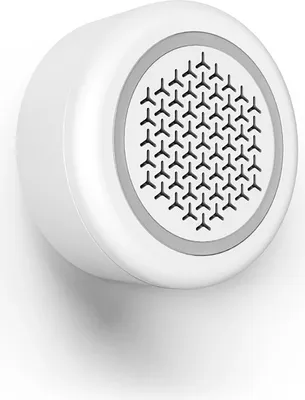 A white smart alarm siren is mounted on a white wall.