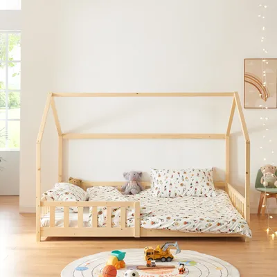 A child's house bed with bedding and stuffed animals.