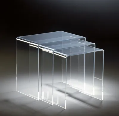 Three clear acrylic nesting tables are shown against a dark background.