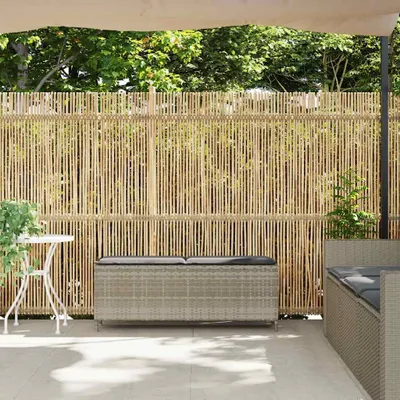 A patio scene with a bamboo fence, outdoor storage bench, and a small table.