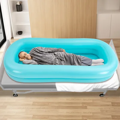 A man is lying in an inflatable bathtub on a bed.