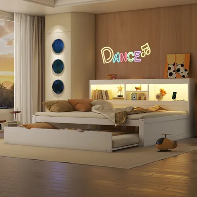 A bedroom scene with a white daybed and a pull-out trundle bed, featuring a headboard with built-in shelves and LED lighting. A neon sign spelling 'Dance' is on the wall.