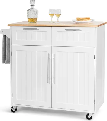 A white kitchen cart with a wooden countertop is shown against a white background. It features two drawers and two cabinet doors, with a towel rack on the side. Two wine glasses and a decanter with liquid are on the countertop, along with a plate with toas