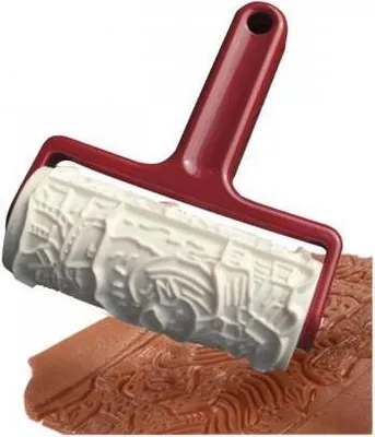 A rolling pin with an embossed pattern is shown pressing into a piece of dough.