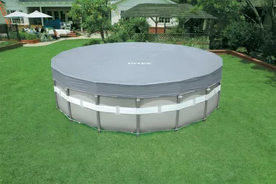 An above-ground swimming pool covered with a tarp in a backyard setting.
