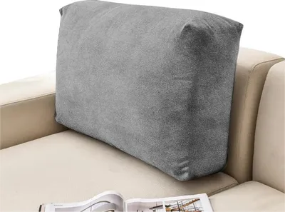 A grey cushion placed on a beige sofa.