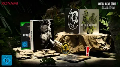 A collection of Metal Gear Solid Delta: Snake Eater Deluxe Edition game boxes and merchandise are displayed on rocks and foliage.